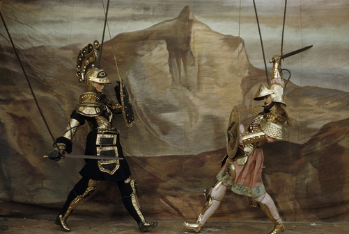 Marionettes dressed in armor enact sword fight.